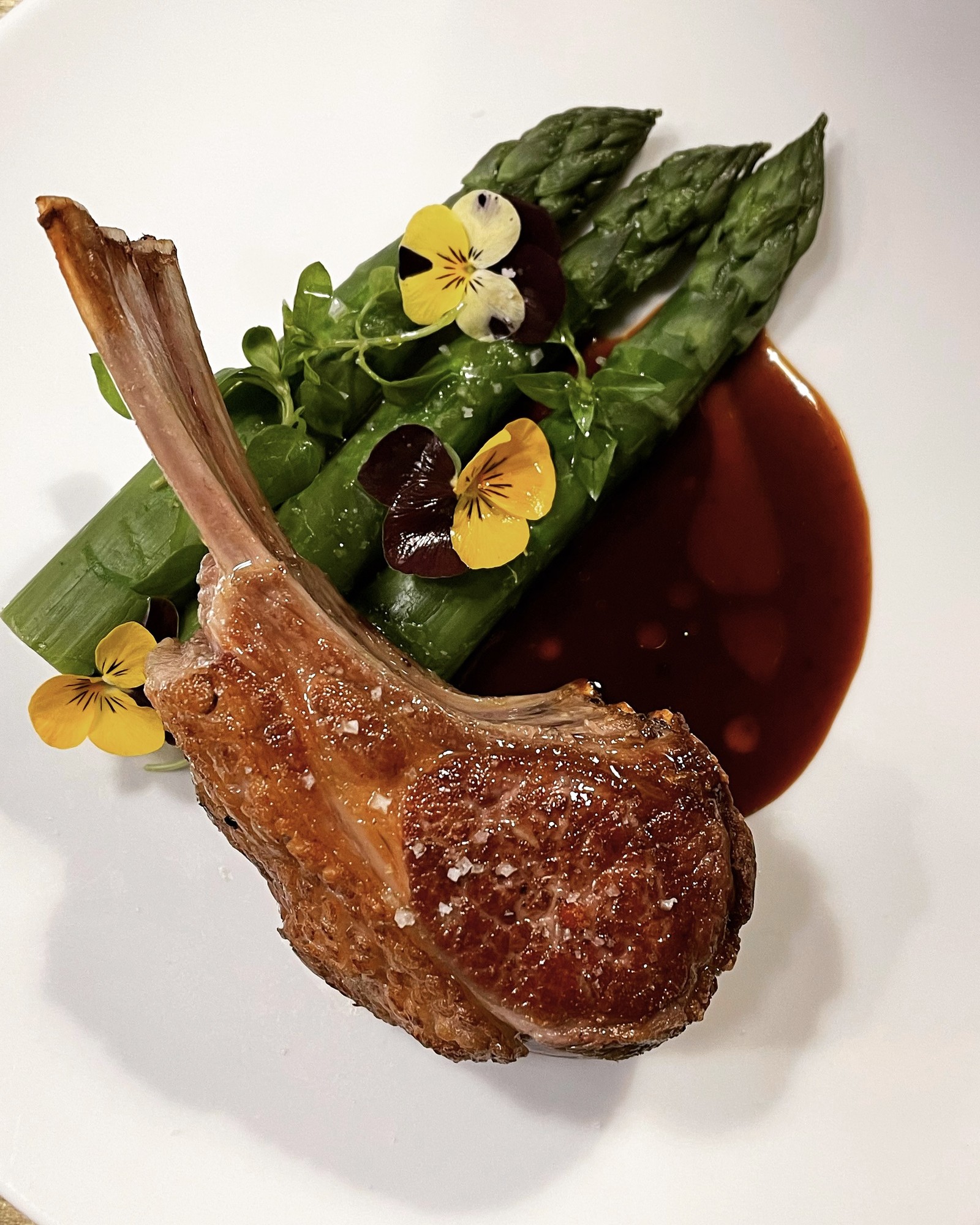 Lamb chop with asparagus, edible flowers and a rich jus