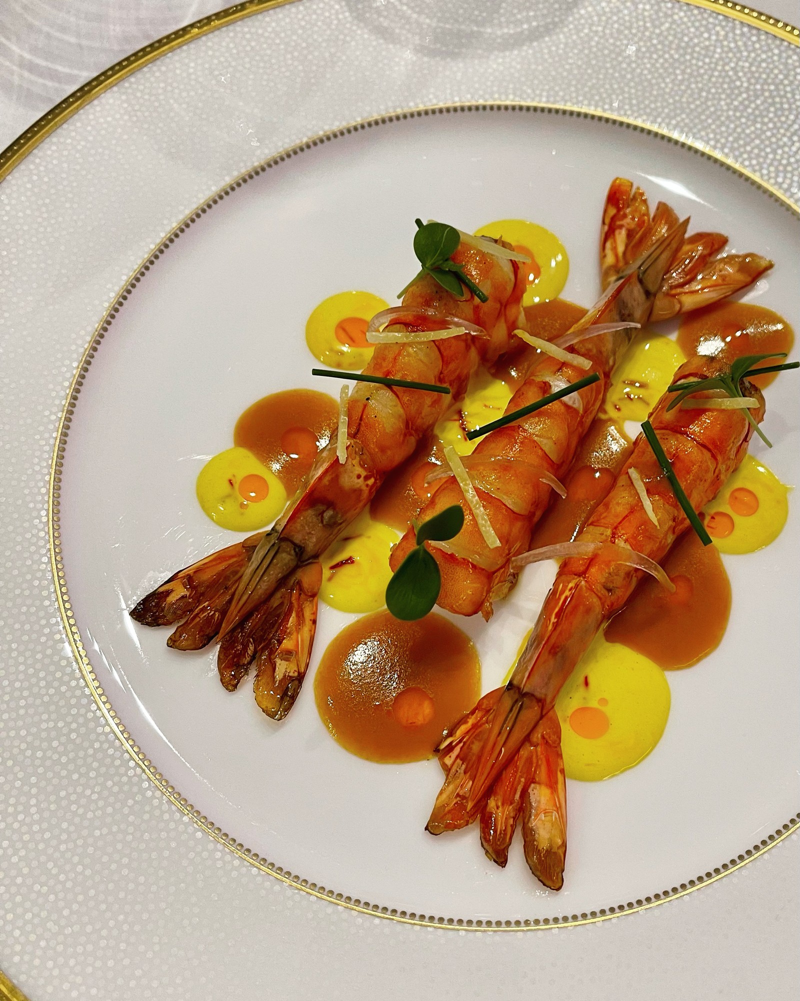 Whole prawns with saffron cream on a gold-rimmed plate