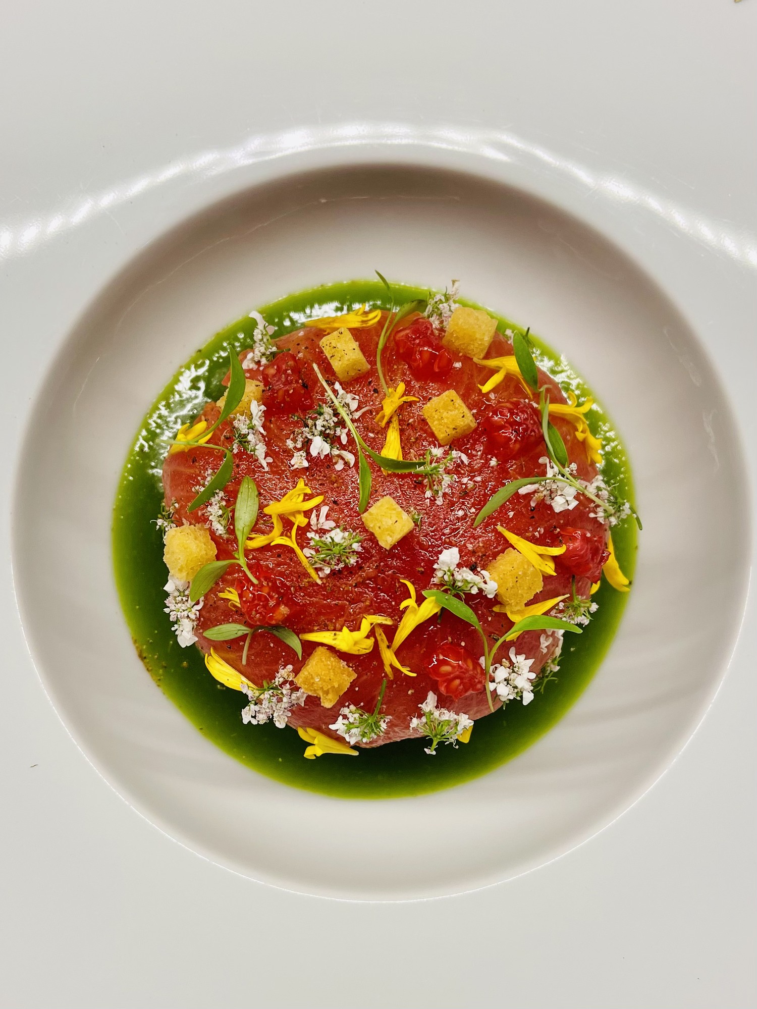 Tuna tartare with green herb oil and edible flowers